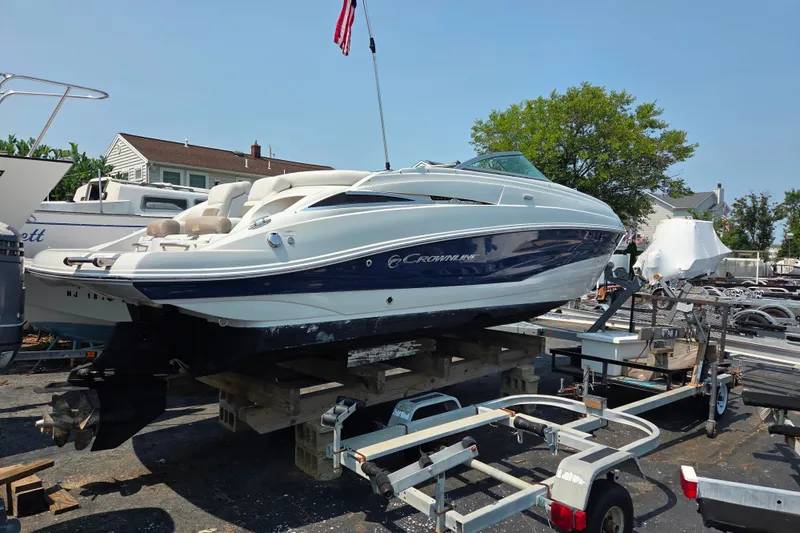 Slide: The Image of 2015 Crownline 255 SS boat on trailer, parked outdoors under clear sky. - 10
