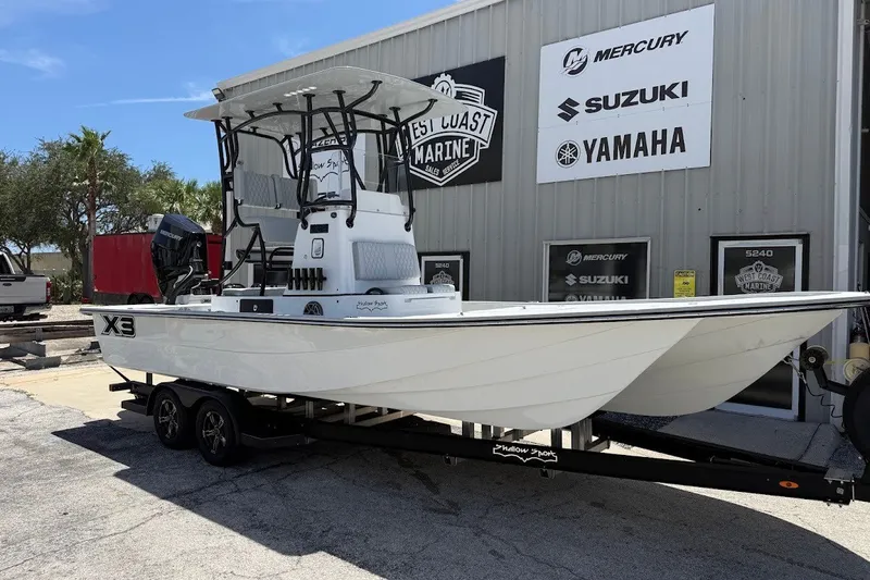 The Image of 2027 Shallow Sport 25 X3 boat on trailer outside marine dealership. - 1
