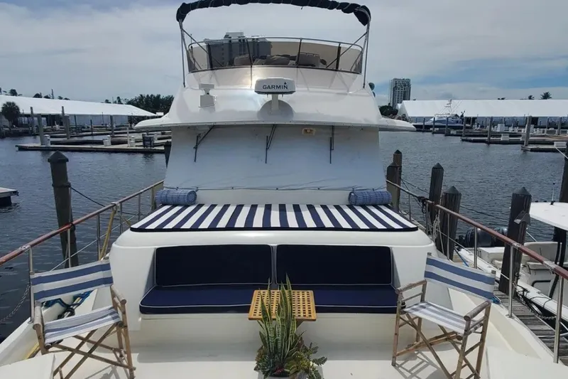 Slide: The Image of 1981 Hatteras 56 Motor Yacht docked, featuring striped seating and deck chairs. - 1