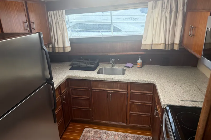 Slide: The Image of 1981 Hatteras 56 Motor Yacht kitchen with wood cabinets, stainless steel appliances, and large window. - 21