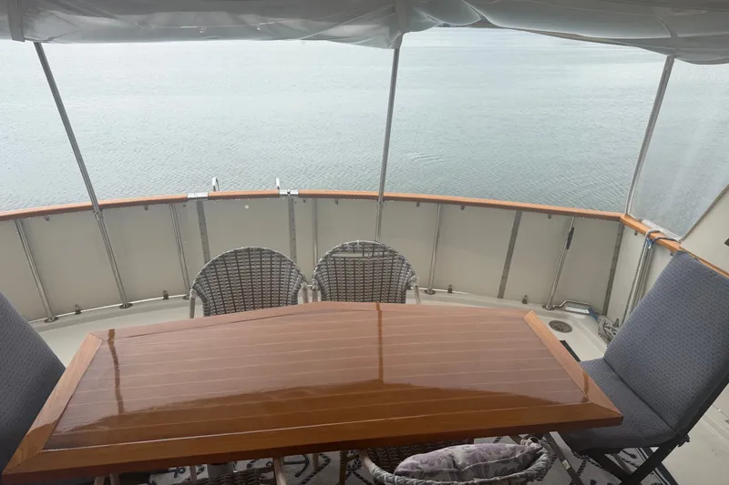Slide: The Image of Aft deck of 1981 Hatteras 56 Motor Yacht with wooden table and chairs overlooking water. - 25
