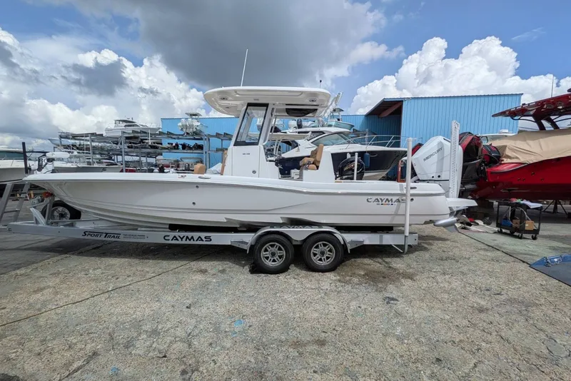 The Image of 2027 Caymas 28 HB boat on trailer at marina, under cloudy sky. - 0