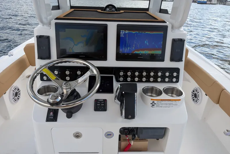 Slide: The Image of 2027 Caymas 28 HB boat dashboard with dual Garmin displays and steering wheel on water. - 8