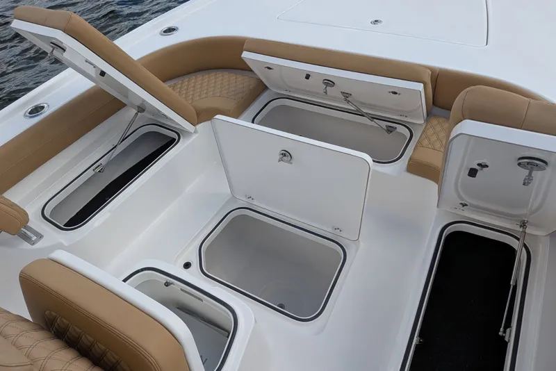 Slide: The Image of 2027 Caymas 28 HB boat with open storage compartments and tan seating. - 15