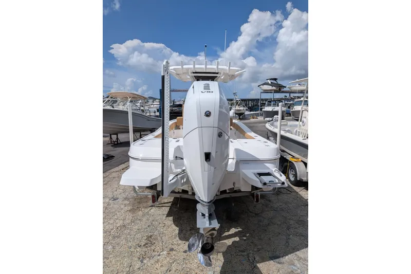 Slide: The Image of 2027 Caymas 28 HB boat with powerful outboard motor, docked under a clear blue sky. - 2