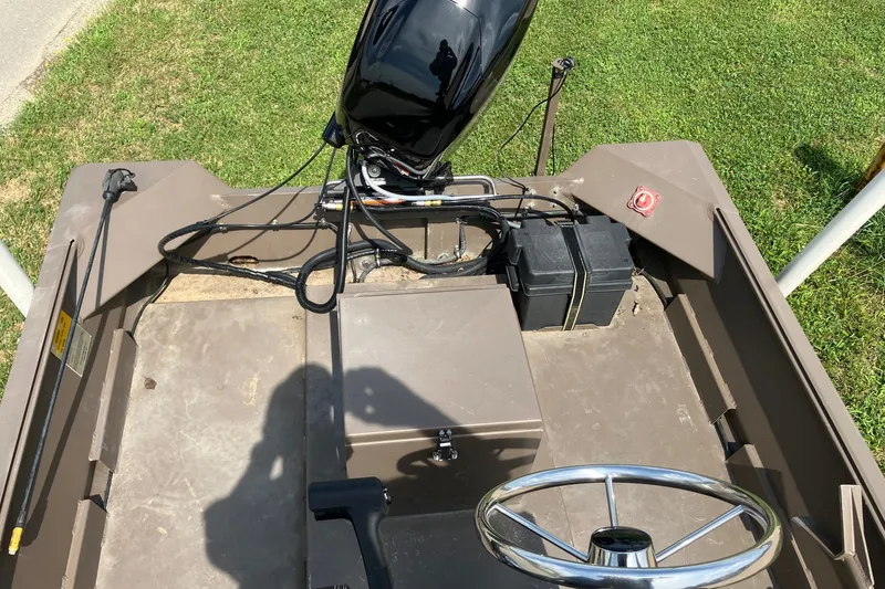 Slide: The Image of 2017 Pro-Drive SBX Series 18' boat interior with steering wheel and motor, on grass. - 14