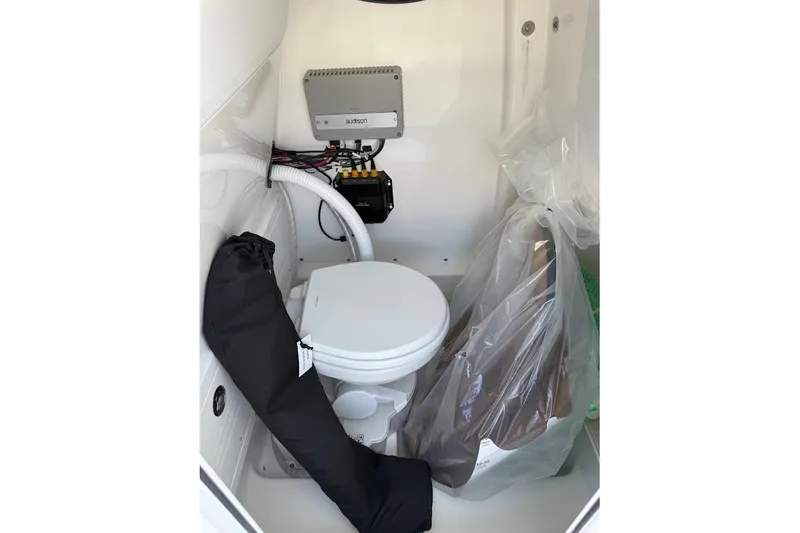 Slide: The Image of Interior of 2027 Sea Pro 245FLXR Sandbar boat featuring a compact marine toilet setup. - 18