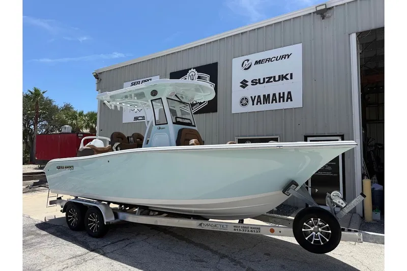 The Image of 2027 Sea Pro 245FLXR Sandbar boat on trailer outside dealership with brand signs. - 1