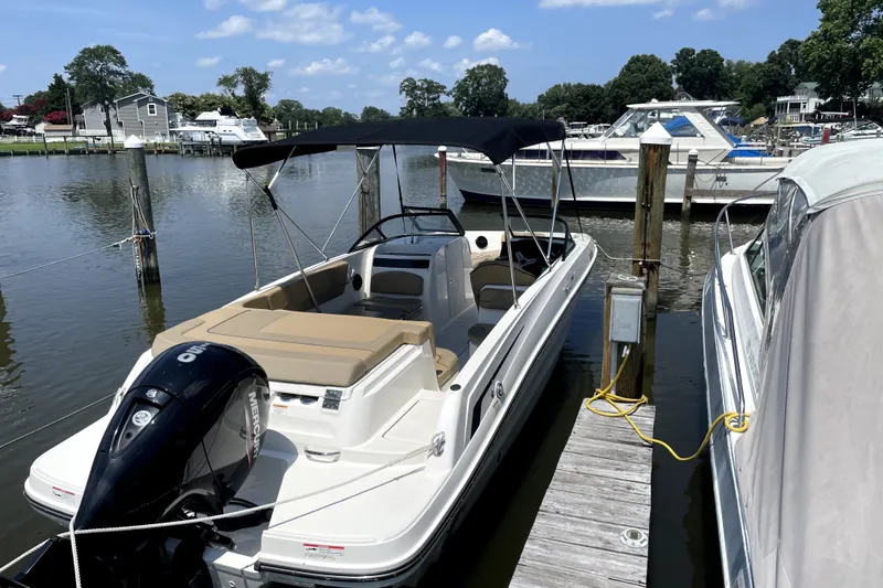 Slide: The Image of 2025 Bayliner VR6 Bowrider OB docked at a marina under a clear sky. - 2
