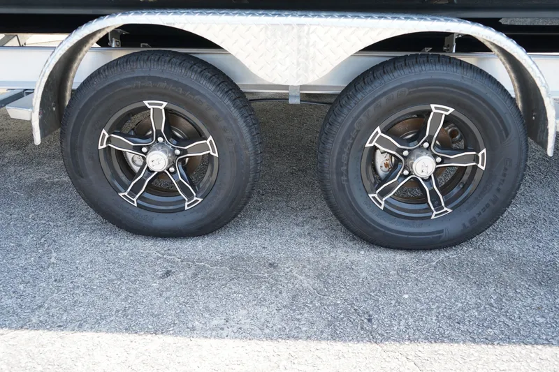 Slide: The Image of Trailer wheels of a 2019 Robalo 246 Cayman boat on pavement. - 14