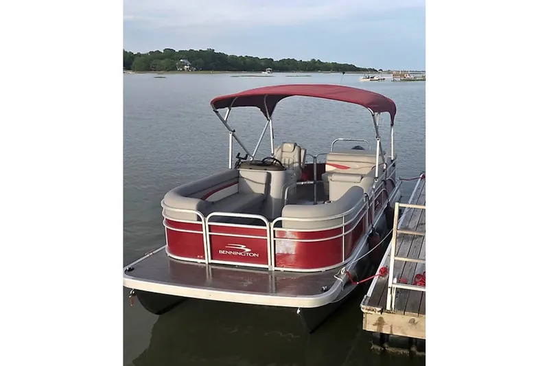 The Image of 2021 Bennington 205E pontoon boat docked on a calm lake. - 0