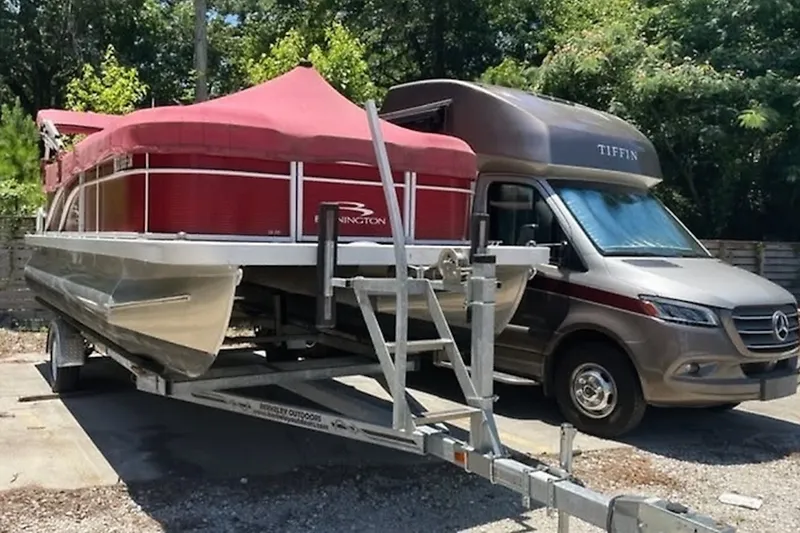 Slide: The Image of 2021 Bennington 205E pontoon boat on trailer beside Tiffin RV in sunny setting. - 3