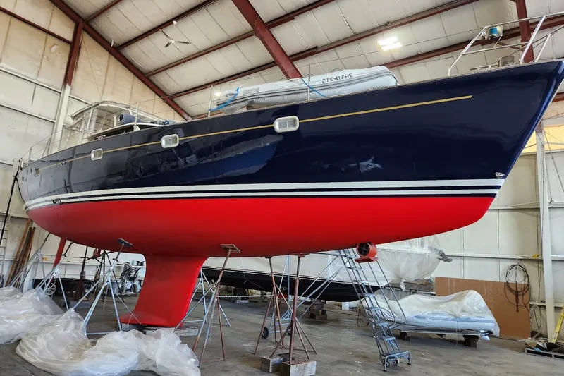 Slide: The Image of 1999 Farr Pilothouse 50 sailboat in dry dock, featuring a sleek red and blue hull. - 35