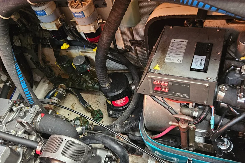 Slide: The Image of Engine room of a 1999 Farr Pilothouse 50 yacht, showcasing mechanical components and wiring. - 19