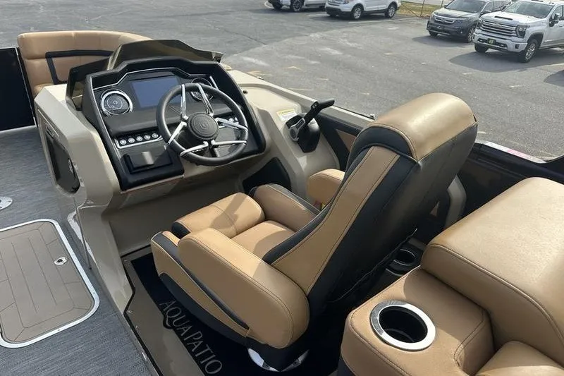 Slide: The Image of 2024 AquaPatio 235 UL boat interior with steering wheel and tan seating. - 15