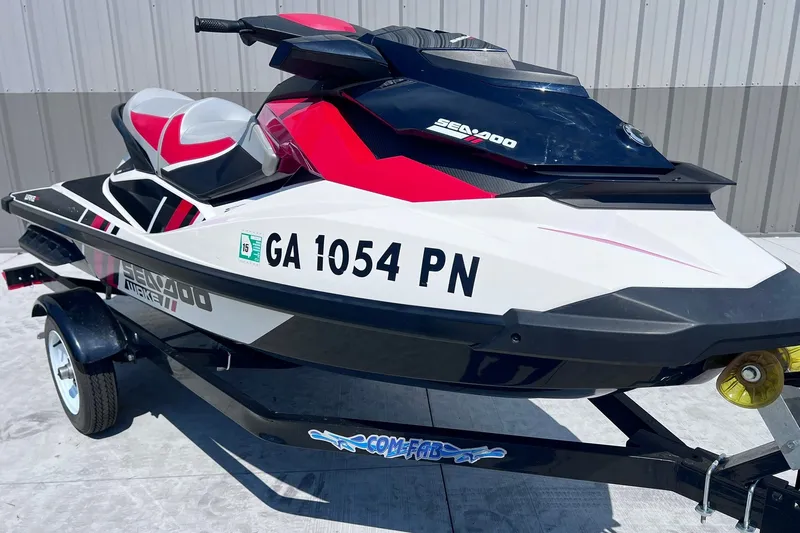 The Image of 2012 Sea-Doo Wake 155 jet ski on trailer, red and white design, parked outdoors. - 1