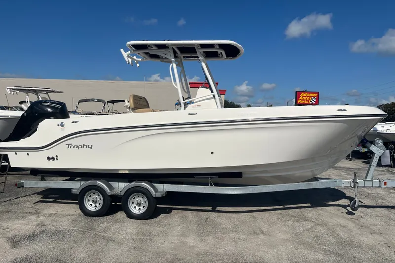 The Image of 2024 Trophy T24 CC boat on trailer, parked outdoors under clear blue sky. - 0