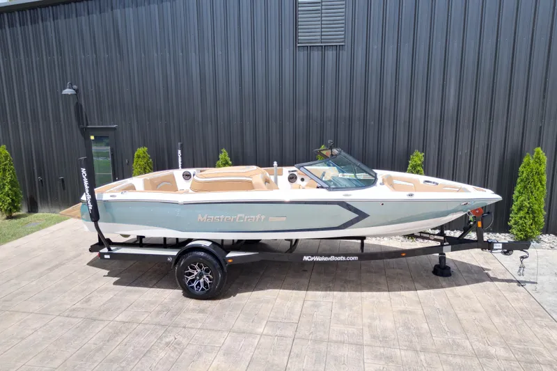 Slide: The Image of 2023 MasterCraft ProStar boat on trailer, parked outdoors near a black building. - 22