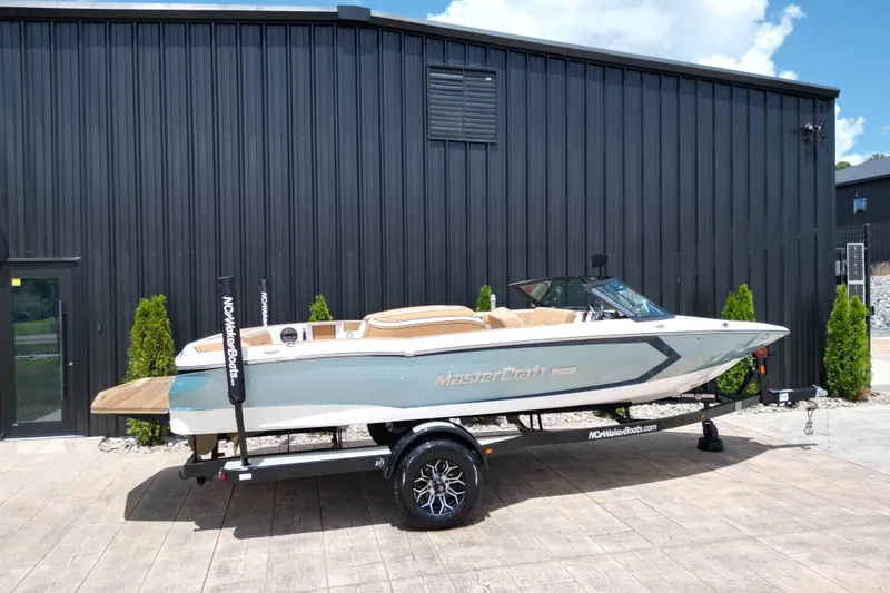 Slide: The Image of 2023 MasterCraft ProStar boat on trailer, parked outside a black building. - 25