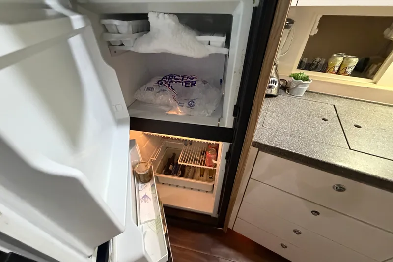 Slide: The Image of Refrigerator inside 1997 Trojan 440 Express yacht, stocked with ice and beverages. - 29