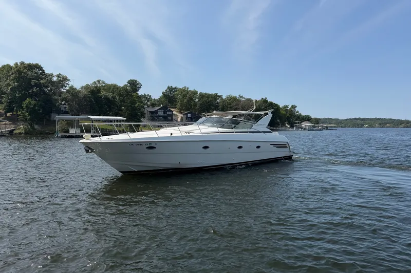 Slide: The Image of 1997 Trojan 440 Express yacht cruising on a scenic lake with wooded shoreline. - 2