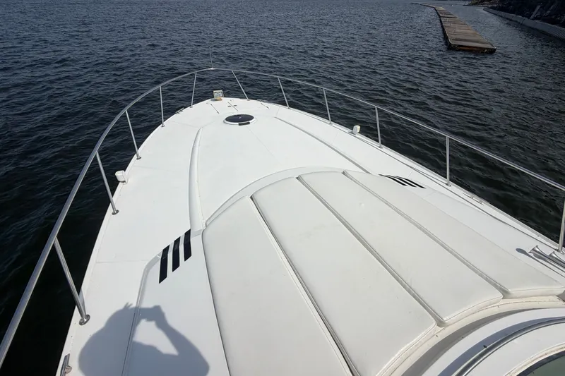 Slide: The Image of Bow view of a 1997 Trojan 440 Express yacht on calm waters. - 7