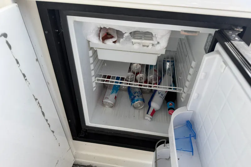 Slide: The Image of Open mini fridge on Trojan 440 Express boat, stocked with drinks and ice. - 18
