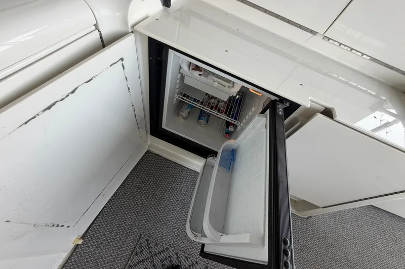 Slide: The Image of Open mini fridge on 1997 Trojan 440 Express boat, showing beverages and snacks inside. - 21