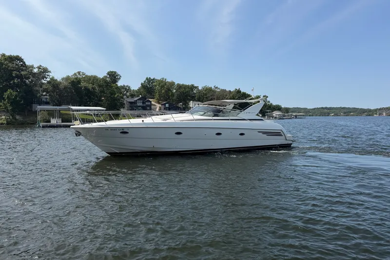 Slide: The Image of 1997 Trojan 440 Express yacht cruising on a serene lake under a clear blue sky. - 1