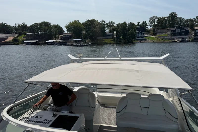 Slide: The Image of 1997 Trojan 440 Express yacht cruising on a scenic lake with a covered deck. - 19