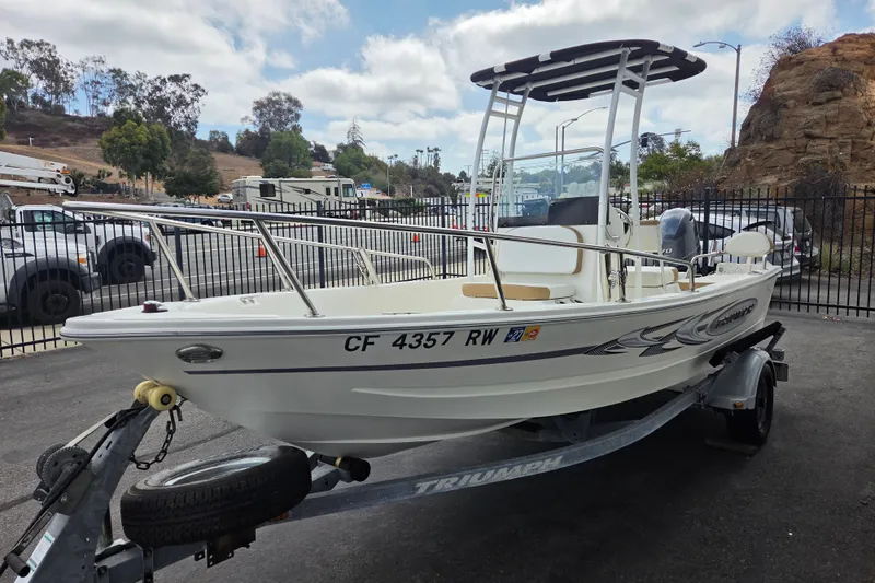 Slide: The Image of 2014 Triumph 170 CC boat on trailer, parked outdoors with scenic background. - 1