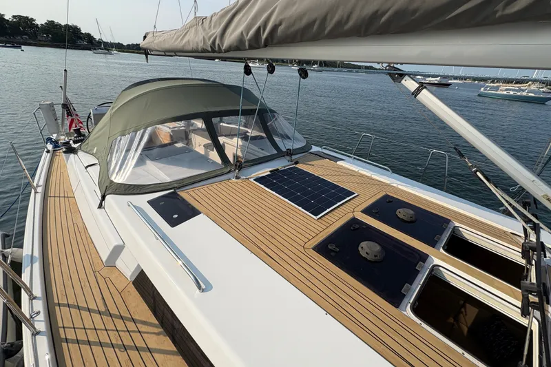 Slide: The Image of 2018 Hanse 455 sailboat with teak deck and solar panel, docked in a serene marina. - 13