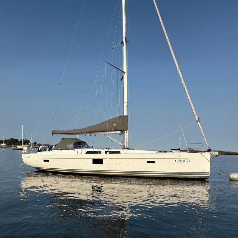 Slide: The Image of A 2018 Hanse 455 sailboat is calmly anchored on the water, surrounded by a serene coastal landscape. - 1