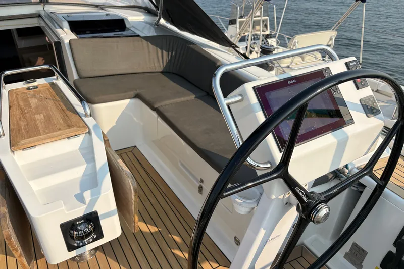Slide: The Image of 2018 Hanse 455 yacht cockpit with steering wheel, navigation display, and cushioned seating. - 9