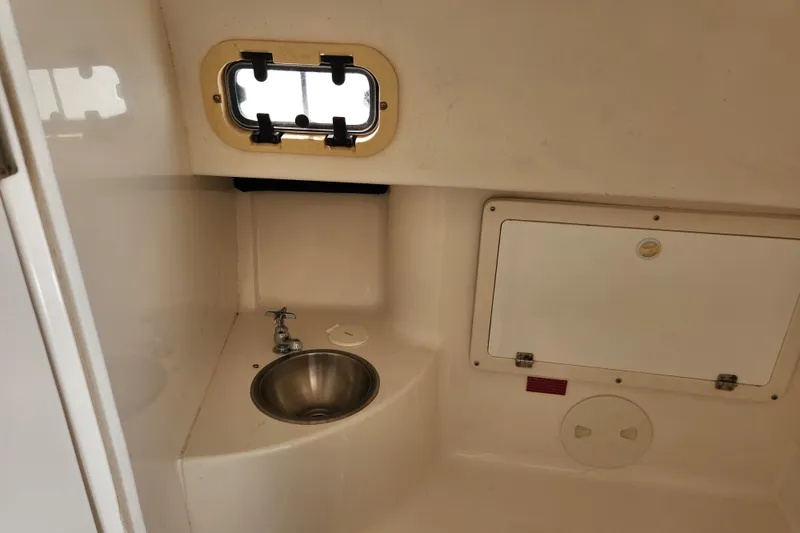 Slide: The Image of 2003 Intrepid 289 Walkaround cabin interior with sink and porthole window. - 35