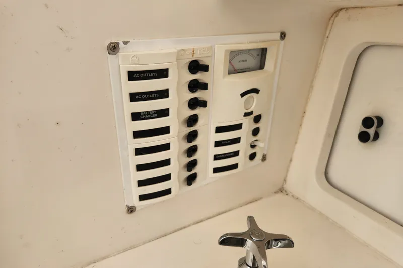 Slide: The Image of Electrical panel on a 2003 Intrepid 289 Walkaround boat, featuring AC outlets and battery charger controls. - 33