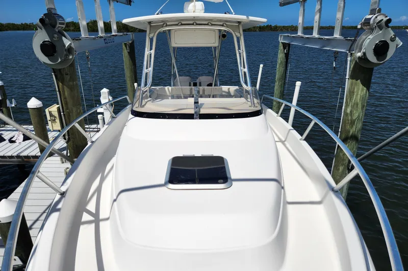 Slide: The Image of 2003 Intrepid 289 Walkaround boat docked, showcasing sleek design and spacious deck. - 21