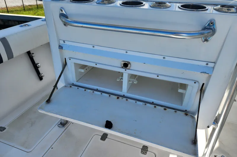Slide: The Image of 2003 Intrepid 289 Walkaround boat interior with open storage compartment and rod holders. - 44