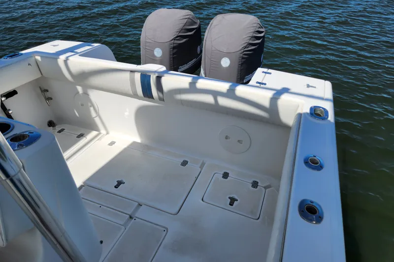Slide: The Image of 2003 Intrepid 289 Walkaround boat deck with dual covered engines on water. - 18