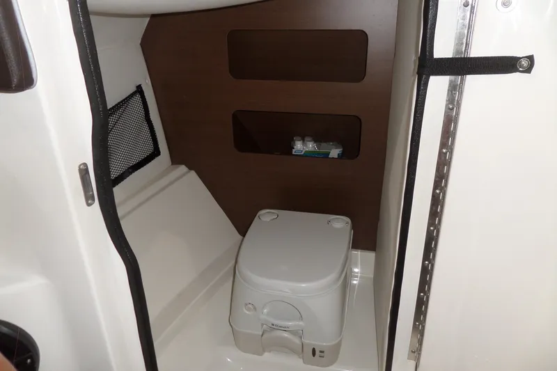 Slide: The Image of 2017 Sea Ray SDX 240 boat interior with compact marine toilet and storage shelves. - 32
