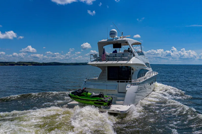 Slide: The Image of Luxury 2004 Marquis 59 yacht cruising with jet ski on open water. - 5