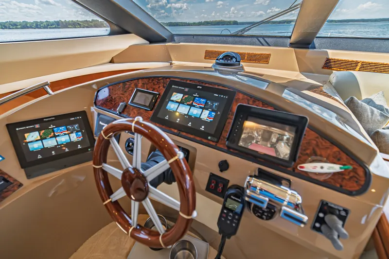 Slide: The Image of Luxurious 2004 Marquis 59 yacht helm with advanced navigation displays and wooden steering wheel. - 53