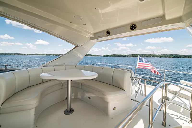 Slide: The Image of Luxurious 2004 Marquis 59 yacht deck with seating, table, and American flag on a sunny day. - 35