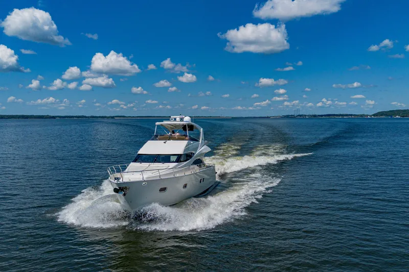 Slide: The Image of Luxury 2004 Marquis 59 yacht cruising on open water under a clear blue sky. - 12