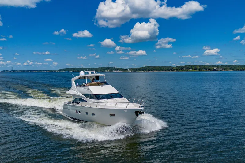 Slide: The Image of Luxurious 2004 Marquis 59 yacht cruising on a serene lake under a clear blue sky. - 11