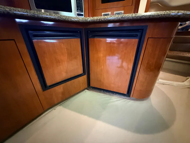 Slide: The Image of The 2005 Sea Ray 420 Sundancer's galley features wooden cabinets and a granite countertop. - 20