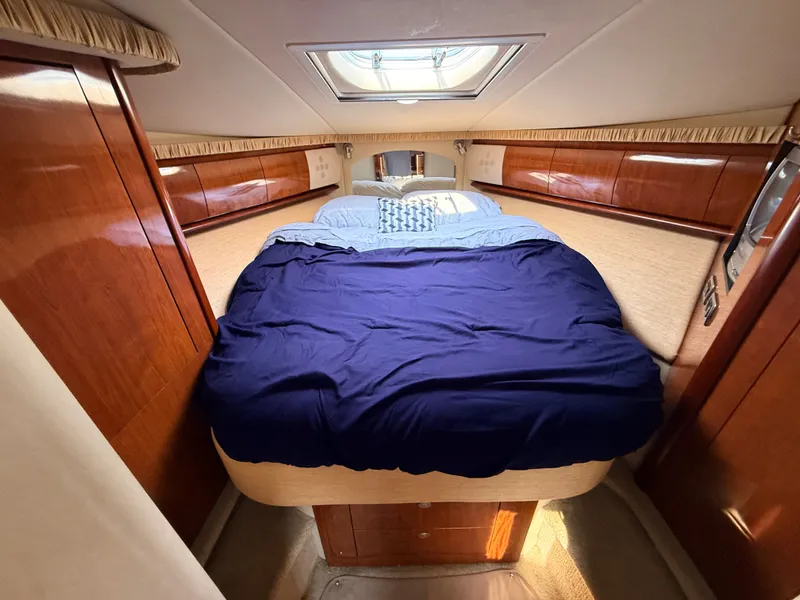 Slide: The Image of The cabin of a 2005 Sea Ray 420 Sundancer with a cozy bed and wood paneling. - 25