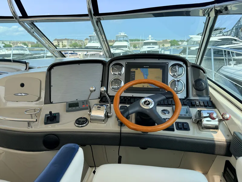 Slide: The Image of The cockpit of a 2005 Sea Ray 420 Sundancer with a wooden steering wheel and navigation system. - 14