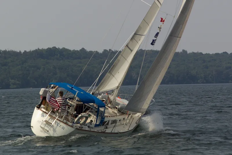 Slide: The Image of 1990 Sabre 34 MK II sailboat on the water, with blue cover and a waving flag. - 0