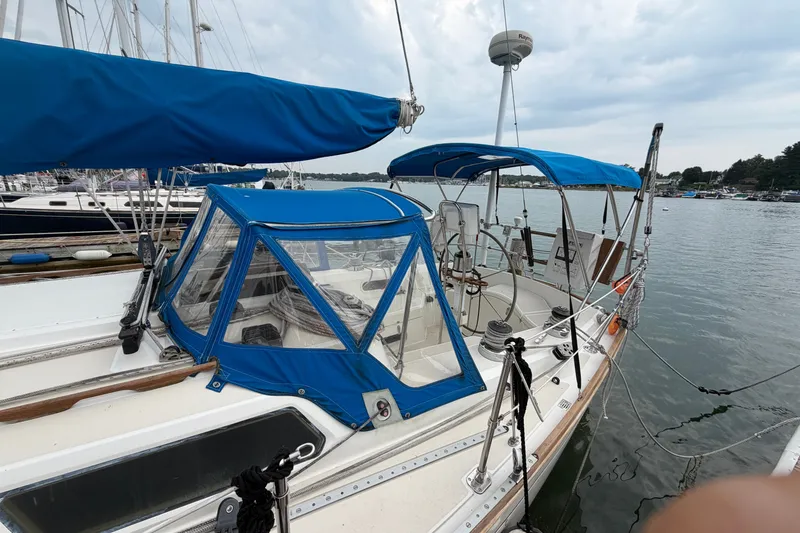 Slide: The Image of 1990 Sabre 34 MK II sailboat docked, featuring blue canvas covers and a spacious cockpit. - 11